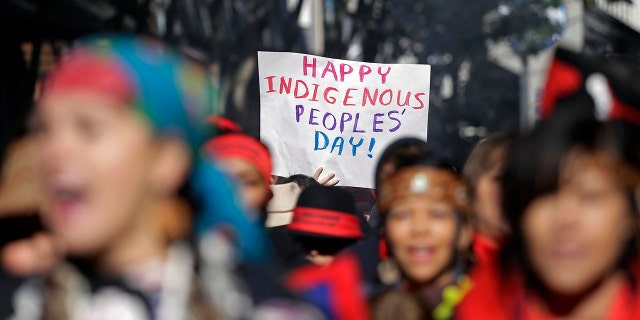 A sign is held aloft during an Indigenous Peoples Day march Monday, Oct. 9, 2017, in Seattle. In 2014, the Seattle City Council voted to stop recognizing Columbus Day and instead turned the second Monday in October into a day of recognition of Native American cultures and peoples. (AP Photo/Elaine Thompson)