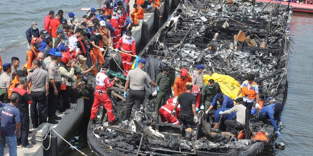 Rescuers search for victims from the wreckage of a ferry that caught fire off the coast of Jakarta after it was docked at Muara Angke Port in Jakarta, Indonesia, Sunday, Jan. 1, 2017. The vessel was carrying more than 230 people from the port to Tidung, a resort island in the Kepulauan Seribu chain, when it caught fire, officials said. (AP Photo/Rhana Ananda)