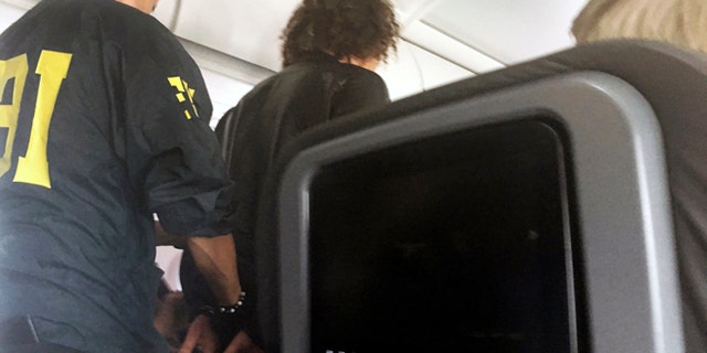 In this photo provided by Donna Basden, a man is escorted off an American Airlines flight after it landed in Honolulu, Friday, May 19, 2017. Federal agents met the plane from Los Angeles when it landed in Honolulu and took the man into custody. (Donna Basden via AP)