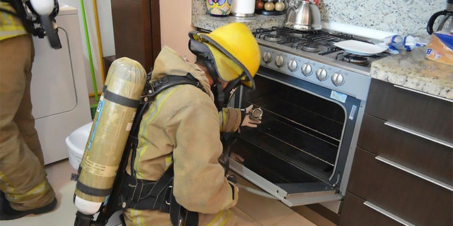 A firefighter examines a gas stove in the rented condo where an Iowa couple and their two children died in Tulum, Mexico.