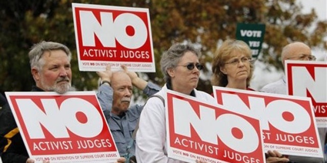 In this Oct. 25, 2010 file photo, demonstrators hold signs during a rally in support of a campaign to remove three state Supreme Court justices who joined in a unanimous ruling legalizing gay marriage in Des Moines, Iowa.