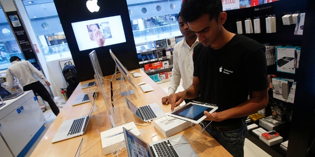 A salesperson unpacks an Apple iPad Mini to test it for a customer in the Apple specialty section of a Croma retail store in Mumbai February 22, 2013. The store offers Apple products including iPhones and iPads on instalment plans. More than four years after it started selling iPhones in India, Apple Inc is now aggressively pushing the iconic device through instalment payment plans that make it more affordable, a new distribution model and heavy marketing blitz. The result: iPhone shipments to India between October and December of 2012 nearly tripled to 250,000 units from 90,000 in the previous quarter, according to an estimate by Jessica Kwee, a Singapore-based analyst at consultancy Canalys. Picture taken February 22, 2013. REUTERS/Vivek Prakash (INDIA - Tags: BUSINESS SCIENCE TECHNOLOGY) - RTR3E840