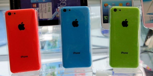 Apple's iPhone 5Cs phones are displayed on racks bearing the logo of China Mobile, at a mobile phone shop in Beijing December 23, 2013.