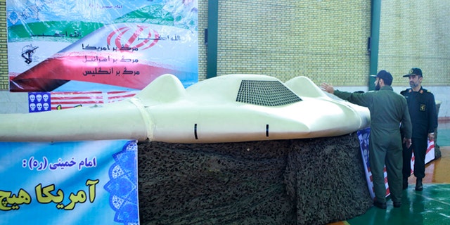 A member of Iran's revolutionary guard point at the U.S. RQ-170 unmanned spy plane that crashed there in 2011. The nation claims it has reverse-engineered the craft, but experts are scoffing. (Reuters)