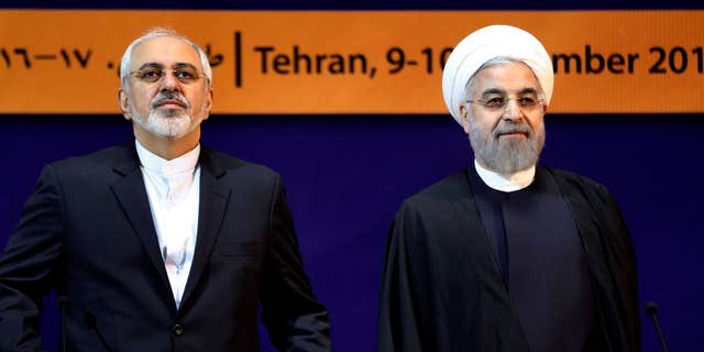 Dec. 9, 2014:  Iranian President Hassan Rouhani, right, and Foreign Minister Mohammad Javad Zarif listen to the Iranian national anthem ahead of the "World Against Violence and Extremism," conference.