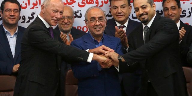 Chief Competitive Officer of Groupe Renault Thierry Bollor, left, Chairman of Industrial Development and Renovation Organization of Iran, IDRO, Mansour Moazami, center, and Negin Group CEO Kourosh Morshed Solouk join hands after signing a deal in Iran.