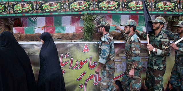 Nov. 4, 2014: Iranian police officers touch the flag-draped coffins of Iranian soldiers who were killed during 1980-88 Iran-Iraq war