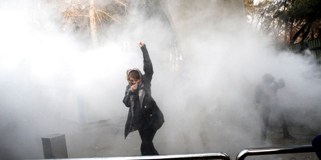 In this photo taken by an individual not employed by the Associated Press and obtained by the AP outside Iran, a university student attends a protest inside Tehran University while a smoke grenade is thrown by anti-riot Iranian police, in Tehran, Iran, Saturday, Dec. 30, 2017. A wave of spontaneous protests over Iran's weak economy swept into Tehran on Saturday, with college students and others chanting against the government just hours after hard-liners held their own rally in support of the Islamic Republic's clerical establishment. (AP Photo)
