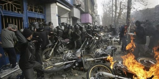 This photo, taken by an individual not employed by the Associated Press and obtained by the AP outside Iran, shows an Iranian protester, left, throwing a rock at police officers in Tehran Dec. 27. (AP Photo)