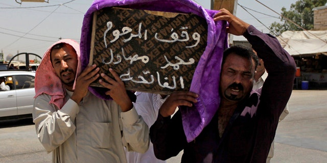 July 1, 2014: Mourners carry the coffin of a victim of violence before his burial in the Shiite holy city of Najaf, 100 miles south of Baghdad, Iraq. Violence has claimed the lives of 2,417 Iraqis in June, making it the deadliest month so far this year, the United Nations said on Tuesday, underlining the daunting challenge the government faces as it struggles to confront Islamic extremists who have seized large swaths of territory in the north and west. Arabic on the coffin reads, "they stood for the late Mohammed Mosawel."
