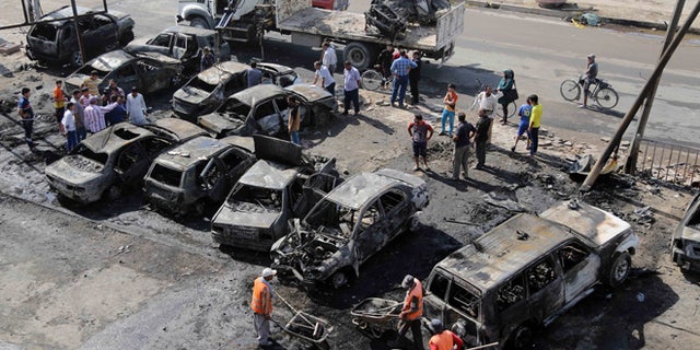 Oct. 27, 2013: Baghdad municipality workers clear debris while citizens inspect the site of a car bomb attack in the Shaab neighborhood of Baghdad, Iraq. Insurgents on Sunday unleashed a new wave of car bombs in Shiite neighborhoods of Baghdad, killing and wounding some dozens of people, officials said