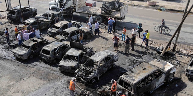Oct. 27, 2013: Baghdad municipality workers clear debris while citizens inspect the site of a car bomb attack in the Shaab neighborhood of Baghdad, Iraq. Insurgents on Sunday unleashed a new wave of car bombs in Shiite neighborhoods of Baghdad, killing and wounding some dozens of people, officials said