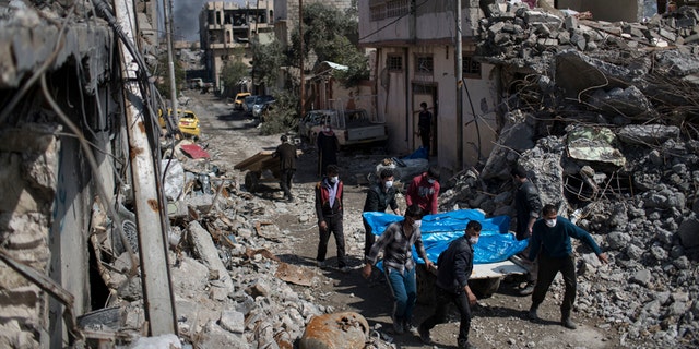 Residents carry the body of several people killed during fights between Iraq security forces and Islamic State on the western side of Mosul, Iraq, Friday, March 24, 2017. Residents of the Iraqi city's neighborhood known as Mosul Jidideh at the scene say that scores of residents are believed to have been killed by airstrikes that hit a cluster of homes in the area earlier this month (AP Photo/Felipe Dana)