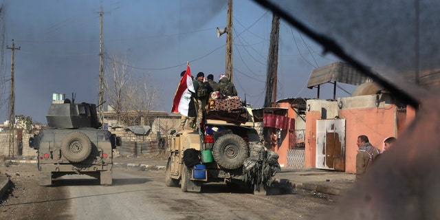 In this photo picture taken through the windshield of Iraq's special forces armored vehicle, Iraqi security forces advance in the eastern side of Mosul, Iraq, Monday, Jan. 16, 2017. Iraqi troops have begun to push Islamic State militants out of the last remaining neighborhoods between government-held territory in the eastern Mosul and the Tigris river which divides the city. (AP Photo/ Khalid Mohammed)