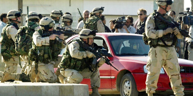 U.S. soldiers aim their rifles during a tense demonstration after a suicide car bomb exploded killing at least 50 people in Iraq.