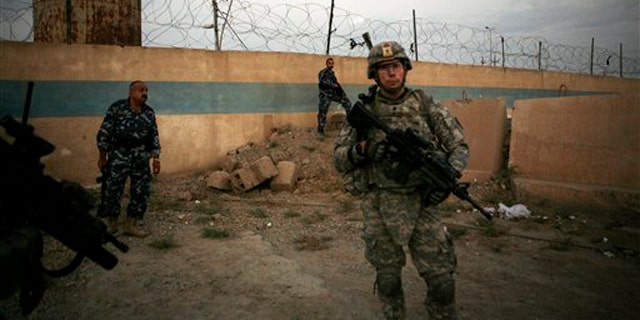 A U.S. Army soldier from 1st Battalion, 14th Infantry Regiment stands with Iraqi policemen outside an Iraqi police station Sept. 1 in Hawija, north of Baghdad, Iraq. (AP Photo)