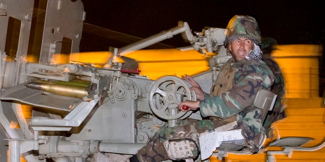 Oct. 31, 2014: An Iraqi Kurdish peshmerga fighter rides on an artillery weapon as he leaves the outskirts of Suruc, Turkey, towards the Turkey-Syria border, on the way to the Syrian city of Kobani
