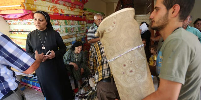 June 27, 2014: An Iraqi nun, second from left, speaks with a Christian man who fled with his family from the Christian villages near Mosul, Iraq, at a school that was turned into a shelter for displaced Christian families, in Ainkawa, a suburb of Irbil, Iraq.