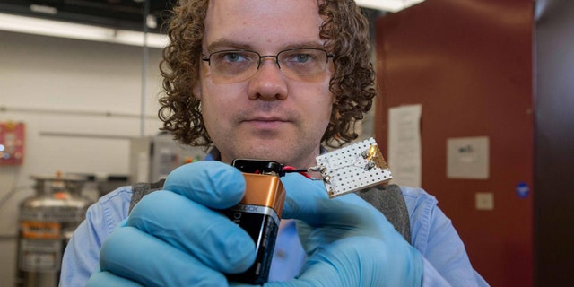 UC graduate student Mark Haase demonstrates the conductivity of carbon nanotube fiber in a battery-powered light.