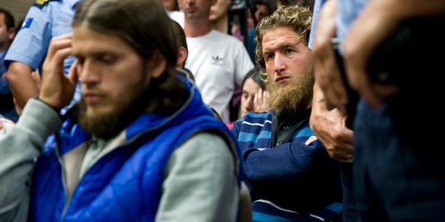 Kosovo police officers stand guard by Arton Ahmeti, left, Leotrim Musliu, right, in court for the foiled attack against the Israeli team in a 2016 qualifying World Cup match in neighboring Albania, in Kosovo's capital Pristina on Friday, May 18, 2018. A Kosovo court has sentenced nine Albanians from a fine to 10 years of jail for planning an attack against the Israeli team in a 2016 qualifying World Cup match. The group, also with members in Albania and Macedonia, was coordinated by two Albanians part of the IS terror group in Syria to hold the attack in November 2016. Police found explosive devices, weapons, electronic equipment and extremist religious literature at their homes. (AP Photo/Visar Kryeziu)