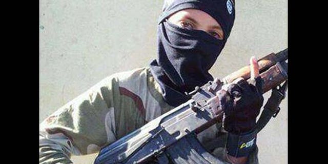 In this undated image posted online and made available on Thursday, Nov. 20, 2014, by Raqqa Is Being Slaughtered Silently, an anti-Islamic State group organization, a child wearing a hat with the Islamic State group logo poses with a weapon in Raqqa, Syria.
