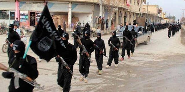 This image posted on a militant website in 2014 shows fighters from ISIS group, marching in Raqqa, Syria.