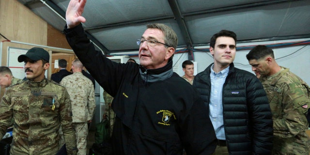 In this Dec. 11, 2016, photo, U.S. Defense Secretary Ash Carter waves to a group of Iraqi and U.S. soldiers during his visit to the Qayara air base, south of Mosul, Iraq.