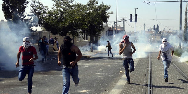 July 4, 2014: Palestinians run away from tear gas as they clash with Israeli security forces during the funeral of 16-year-old Mohammed Abu Khdeir in Jerusalem.