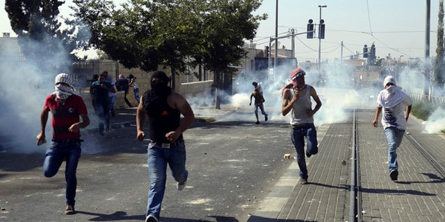 July 4, 2014: Palestinians run away from tear gas as they clash with Israeli security forces during the funeral of 16-year-old Mohammed Abu Khdeir in Jerusalem.