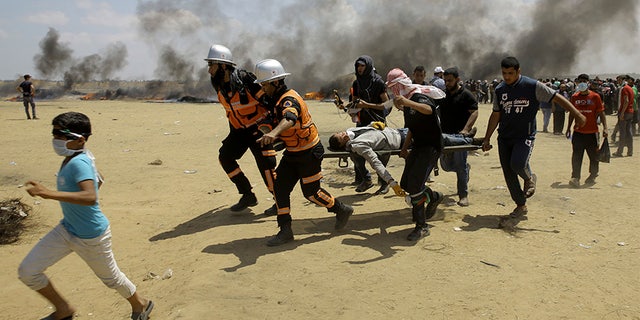 May 14, 2018: Palestinian medics and protesters evacuate a wounded man during a protest at the Gaza Strip's border with Israel, east of Khan Younis, Gaza Strip.