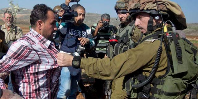 Dec. 10, 2014: An Israeli soldier pulls a Palestinian during a demonstration against Israeli settlements in the village of Turmus Aya near the West Bank city of Ramallah.