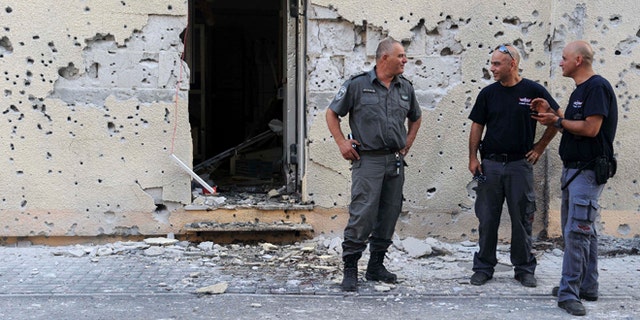 Aug. 22, 2013: Israeli policemen stand in front of a house damaged by a rocket fired from Lebanon in Shavei Tzion outside Nahariya in northern Israel. Military spokesman Lt. Col. Peter Lerner said Thursday that three rockets landed in northern Israel, while one was shot down.
