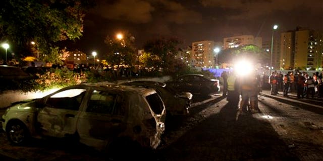 Oct. 29, 2011: Israeli paramedics and security officers work next to destroyed cars at a site where a rocket fired from the Gaza Strip hit in Ashdod, southern Israel. Israeli aircraft struck at Palestinian militants on Saturday, killing five, while militants responded with a volley of rockets which injured several Israeli civilians, Israeli and Palestinian officials said.