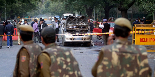 Feb. 13, 2012: Indian policemen watch security and forensic officials examine a car belonging to the Israel Embassy after an explosion tore through that in New Delhi, India.