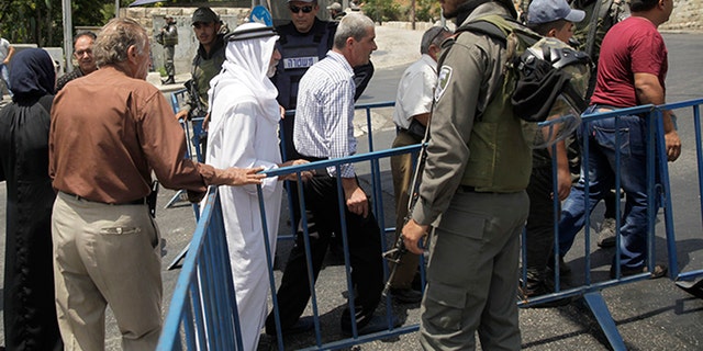 Israeli border police officers stand guard as Palestinians pass a checkpoint near Jerusalem's Old City Friday.