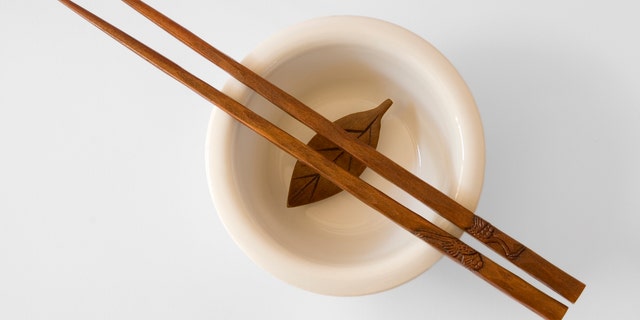 Chopsticks in a bowl with wooden leaf - with clipping path