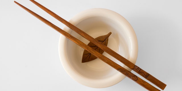 Chopsticks in a bowl with wooden leaf - with clipping path