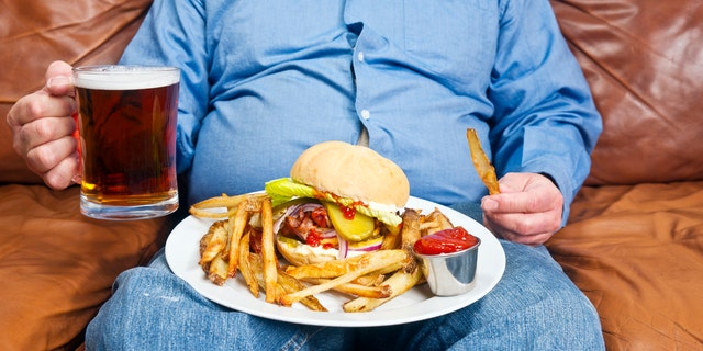 An overweight man eats an unhealthy meal.