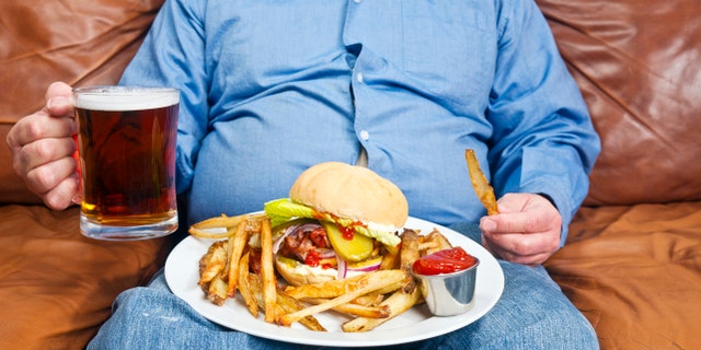 An overweight man eats an unhealthy meal.