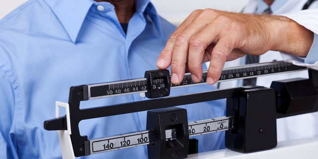 XXXL. Doctor checking weight of patient.