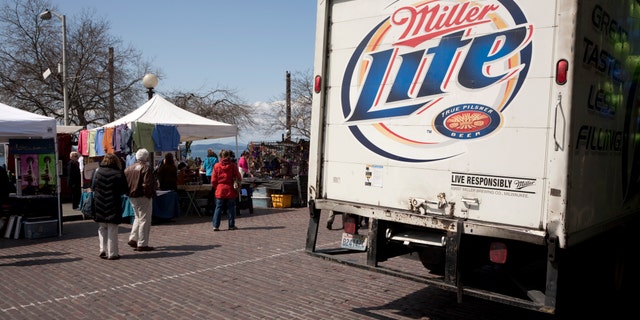 Seattle, United States - April 22, 2011: Tourists mill about and around a beer delivery truck. Brand is Miller Lite. Seattle Pike Place Market, outdoor market crafts stands in the background.