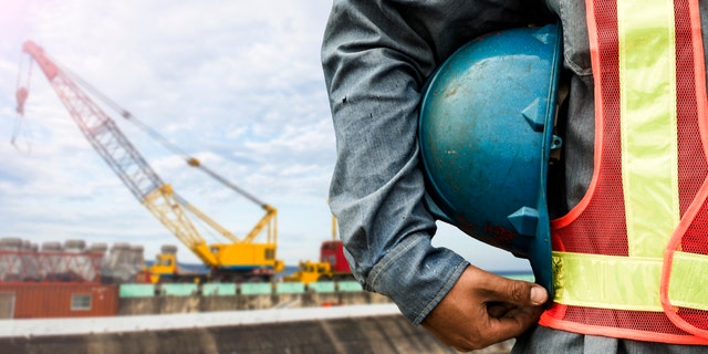 construction worker checking location site with crane on the background