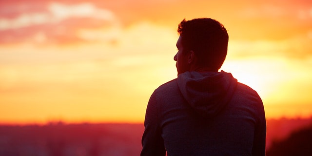 Young man is looking at the sunrise