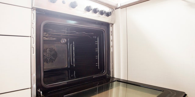 Modern empty oven, black inside, opened door.