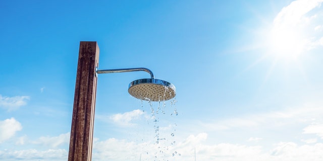 shower head with water droplets on seashore and blue sky background