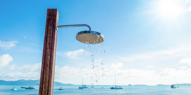 shower head with water droplets on seashore and blue sky background