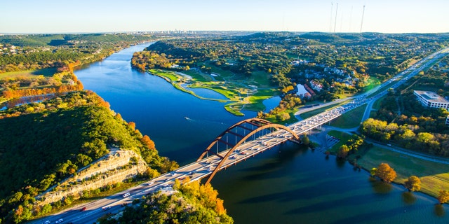 This part of Texas — Texas Hill Country — is shown glowing with bright colors in a fall image. This is an aerial and breathtaking image of the Pennybacker Bridge built in 1984; it completes the Austin vibe of West Texas Hill Country.