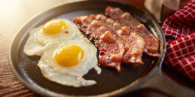 fried bacon and eggs in iron skillet shot with selective focus
