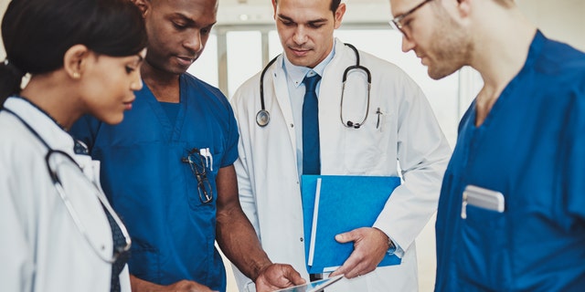 Team of multiracial doctors at hospital discussing a patient, Doctors using tablet