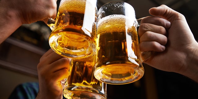 Hands of three men toasting with beer